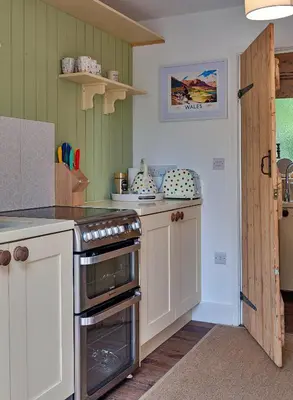 a kitchen with white cabinets and a stove top oven at Finest Retreats - Shrawardine Train Carriage in Shrawardine
