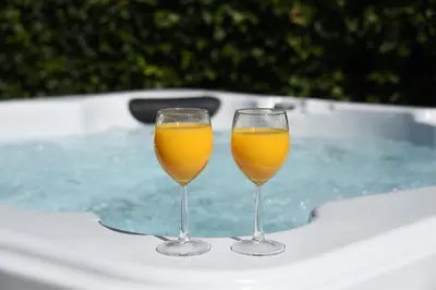 two glasses of orange juice sitting on top of a tub at Tawny Owl Lodge in Rhayader