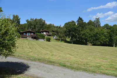 a large grassy field with houses in the background at Tawny Owl Lodge in Rhayader