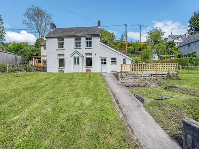 an old white house with a grass yard at Jackdaw Cottage in Knighton