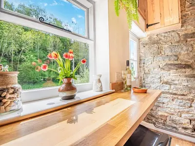 a kitchen with a window and flowers on a counter at Jackdaw Cottage in Knighton