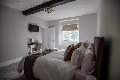 a bedroom with a bed with white sheets and pillows at The Berwyn Arms in Corwen