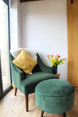 a green chair with a green ottoman in a room at The Tin Shed in Rhayader
