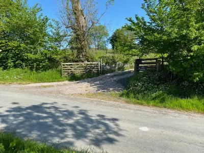 a fence on the side of a road with trees at 3-Bed Cottage Near Lake Vyrnwy Garden & PetsOk in Hirnant