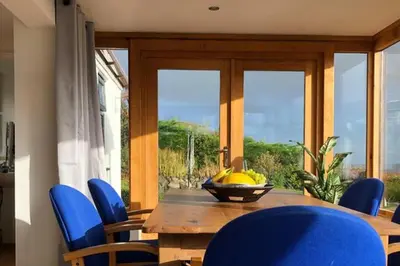 a dining room table with blue chairs and a bowl of bananas at 3-Bed Cottage Near Lake Vyrnwy Garden & PetsOk in Hirnant