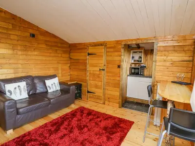 a living room with a leather couch and a table at Tree House in Aberaeron