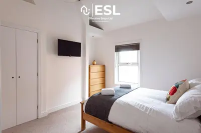 a bedroom with a bed and a tv on a wall at 2 Bedroom Terrace Cottage, Parking, 5 minutes drive to Royal Shrewsbury Hospital in Shrewsbury