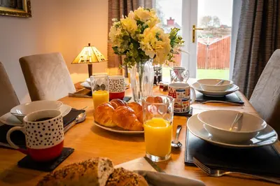 a wooden table with breakfast food and orange juice at Town Location for Shrewsbury with 3 Bedrooms - Pass the Keys in Shrewsbury