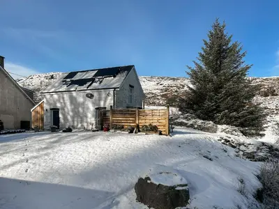 an old barn in the snow with a pine tree at The Barn in Llangwm