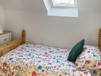 a bed with a floral comforter and a window at The Barn in Llangwm