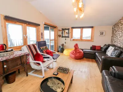 a living room with a couch and a piano at Sibrwd Y Mor in Harlech