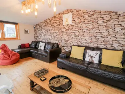 a living room with couches and a stone wall at Sibrwd Y Mor in Harlech