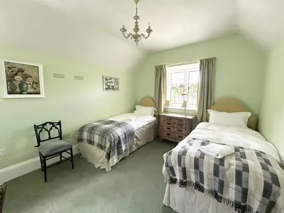a bedroom with two beds and a chair and a window at Trillow House, Clungunford, Ludlow in Clungunford