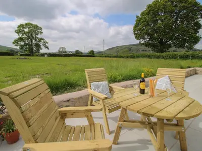 two chairs and a wooden table with a bottle of wine at Bethania in Oswestry