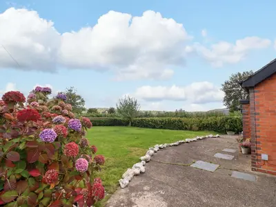 a garden with flowers and a brick building at Bethania in Oswestry