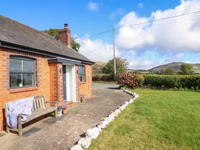 a brick house with a bench in front of it at Bethania in Oswestry