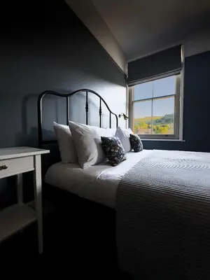 a bedroom with a bed with white pillows and a window at Riversdale House Bed & Breakfast in Llangollen