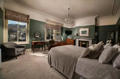 a bedroom with a bed and a desk and a chair at Riversdale House Bed & Breakfast in Llangollen