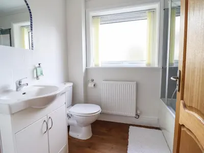 a bathroom with a toilet and a sink and a window at Tan Yr Allt in Welshpool