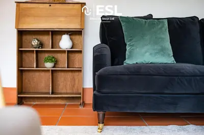 a blue couch with a green pillow next to a book shelf at Quarry View Garden Studio in Shrewsbury with Parking in Shrewsbury