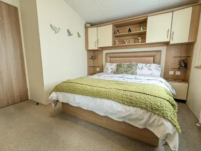 a bedroom with a bed with a wooden headboard at Peacehaven, Ynyslas, Borth in Borth