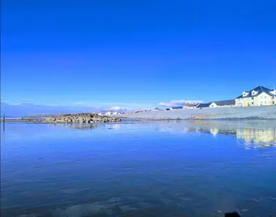 a large body of water with houses in the background at Peacehaven, Ynyslas, Borth in Borth