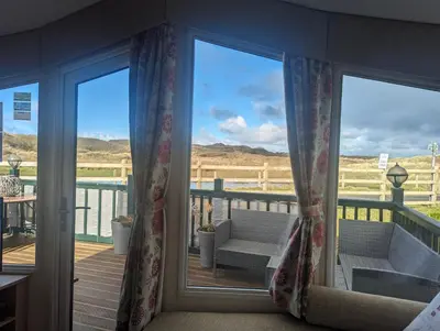 a sliding glass door with a view of a deck at Peacehaven, Ynyslas, Borth in Borth