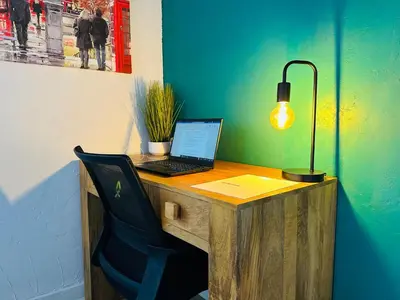 a laptop computer sitting on a wooden desk with a chair at Trawsfynydd Stone Cottage in Trawsfynydd