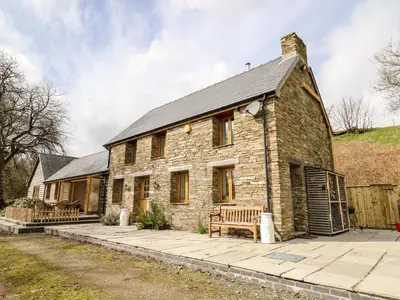 a stone house with two benches in front of it at The Orchard in Knighton