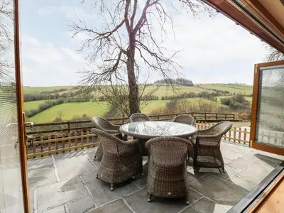 a patio with a table and chairs on a balcony at The Orchard in Knighton