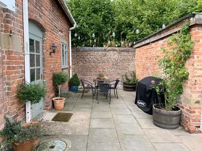 a patio with a table and chairs in a brick building at The Little Coach House in Wales in Newtown