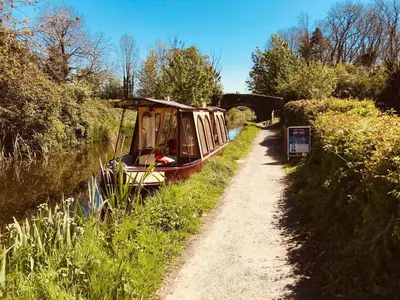 a boat on a river next to a path at Willowdene shepherds hut in Oswestry
