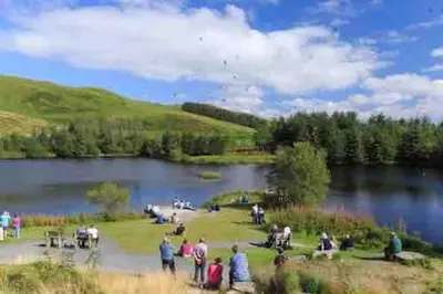 a group of people standing around a lake at Y Villa Môr in Llanarth