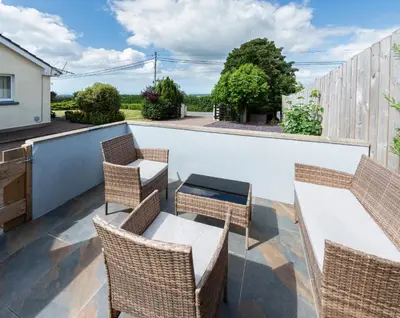 a patio with wicker chairs and tables on a roof at Y Villa Môr in Llanarth