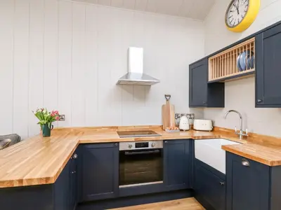 a kitchen with blue cabinets and a sink and a clock at Doe Lodge in Rhayader