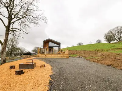 a small cabin on a hill with a gravel road at Doe Lodge in Rhayader