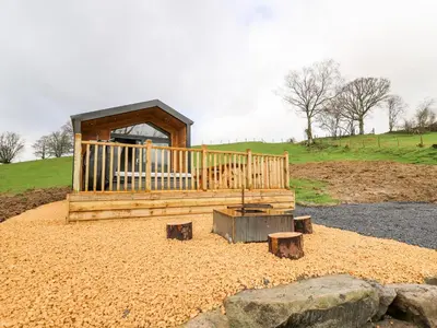 a wooden cabin with a porch and some rocks at Fawns Rest in Rhayader