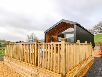 a small house with a wooden fence at Fawns Rest in Rhayader