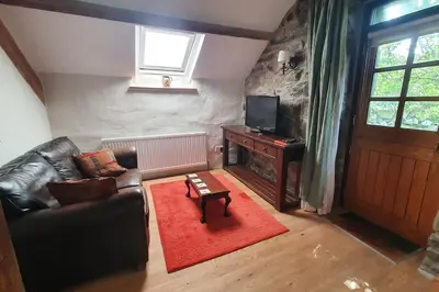 a living room with a leather couch and a television at The Hayloft Llwyndu in Barmouth