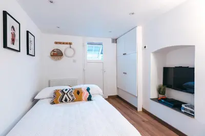 a white bedroom with a bed and a flat screen tv at Quaint Georgian house with Parking & Huge Garden 10 mins walk from town in Shrewsbury