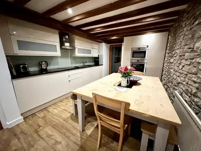 a kitchen with a wooden table and a stone wall at Hay On Wye Welsh Townhouse in Hay centre in Hay-on-Wye