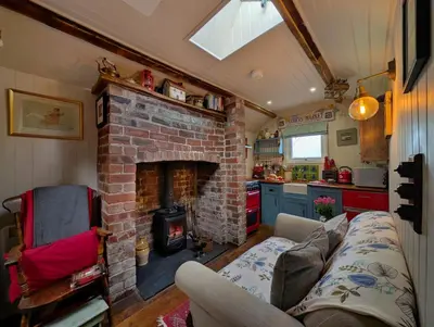 a living room with a brick fireplace and a couch at Romantic country cabin with log burner, spectacular views, spa hot tub - Brecon Beacons National Park dog friendly in Llangadog