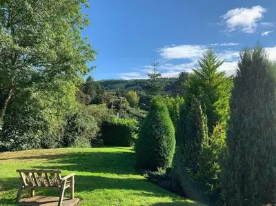 a wooden bench sitting in the grass in a garden at Romantic Log Cabin With Hot Tub in Leominster