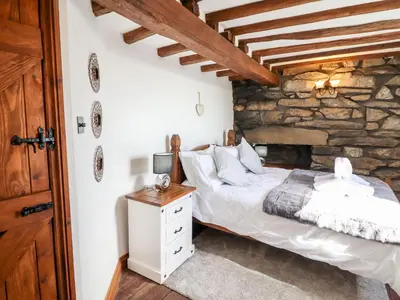 a bedroom with a bed and a stone wall at Ty'n-Y-Ffynnon Cottage in Barmouth
