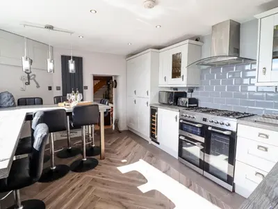 a kitchen with white cabinets and a table with chairs at Ty'n-Y-Ffynnon Cottage in Barmouth