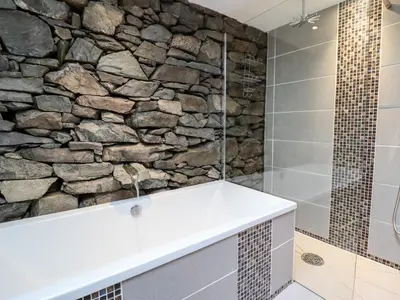 a stone wall in a bathroom with a shower at Ty'n-Y-Ffynnon Cottage in Barmouth