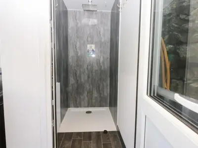 a small bathroom with a shower with a wooden floor at Ty'n-Y-Ffynnon Cottage in Barmouth