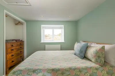 a bedroom with a bed and a dresser and a window at Tranquil 1 bedroom cottage 15 mins drive to sea in Mydroilin