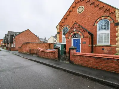 a brick building with a blue door on a street at Wesleyan House in Oswestry