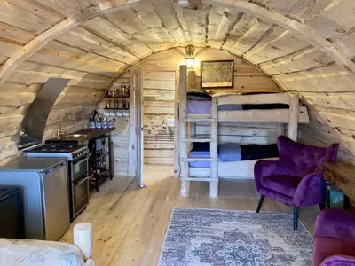 a log cabin bedroom with a bunk bed and a kitchen at The Prancing Moose in Ystrad Meurig
